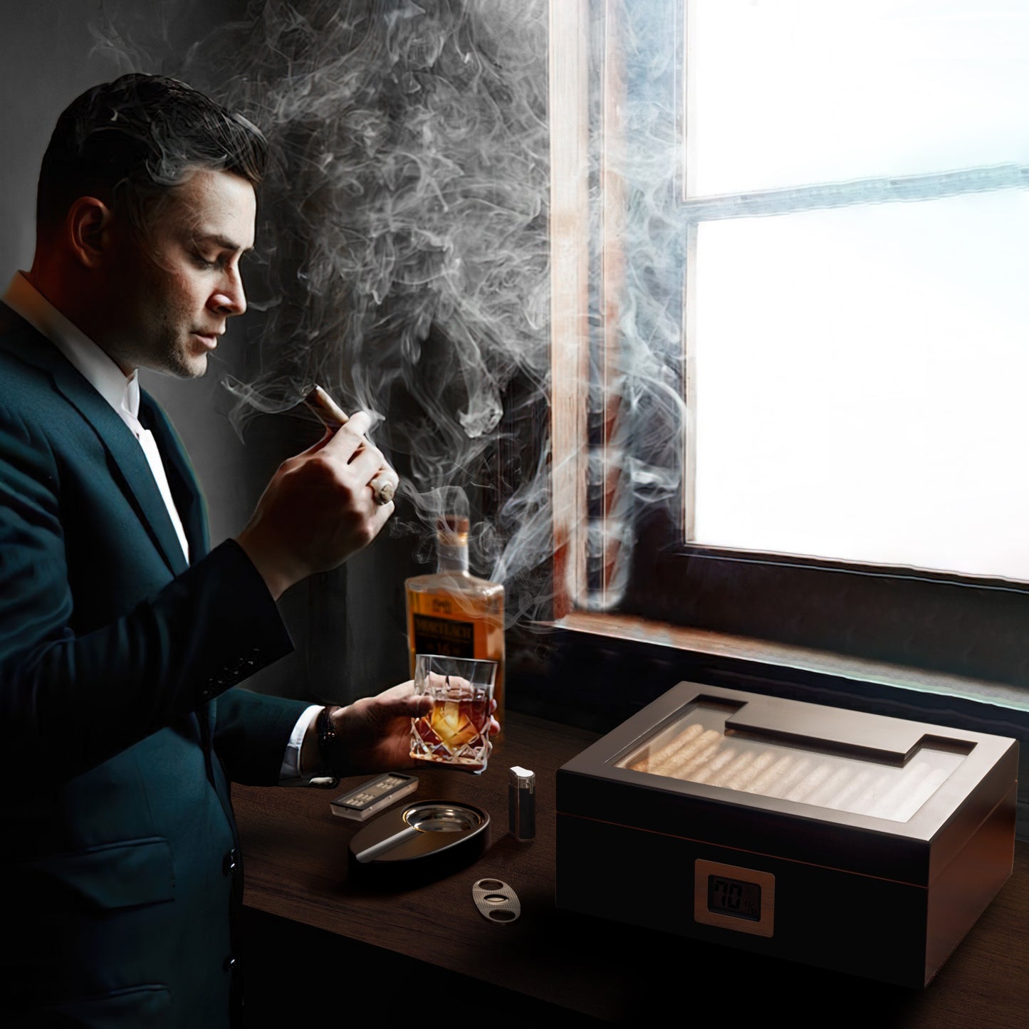 A moody luxury lifestyle shot of a man in a tailored suit smoking a cigar and holding a whiskey glass, with the humidor, ashtray, cutter, and accessories arranged on a wooden desk by a window, surrounded by cigar smoke.