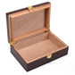 An empty, open cigar humidor revealing its full light brown cedar wood interior, with gold-colored metal hinges and a front clasp visible.