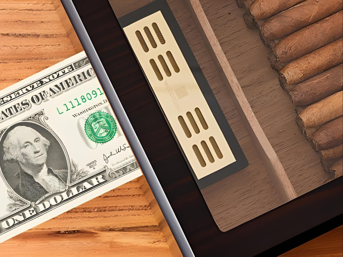 A size comparison shot of the crystal gel humidifier placed next to a US one-dollar bill, demonstrating its compact dimensions while fitting seamlessly inside the humidor’s cedar compartment.