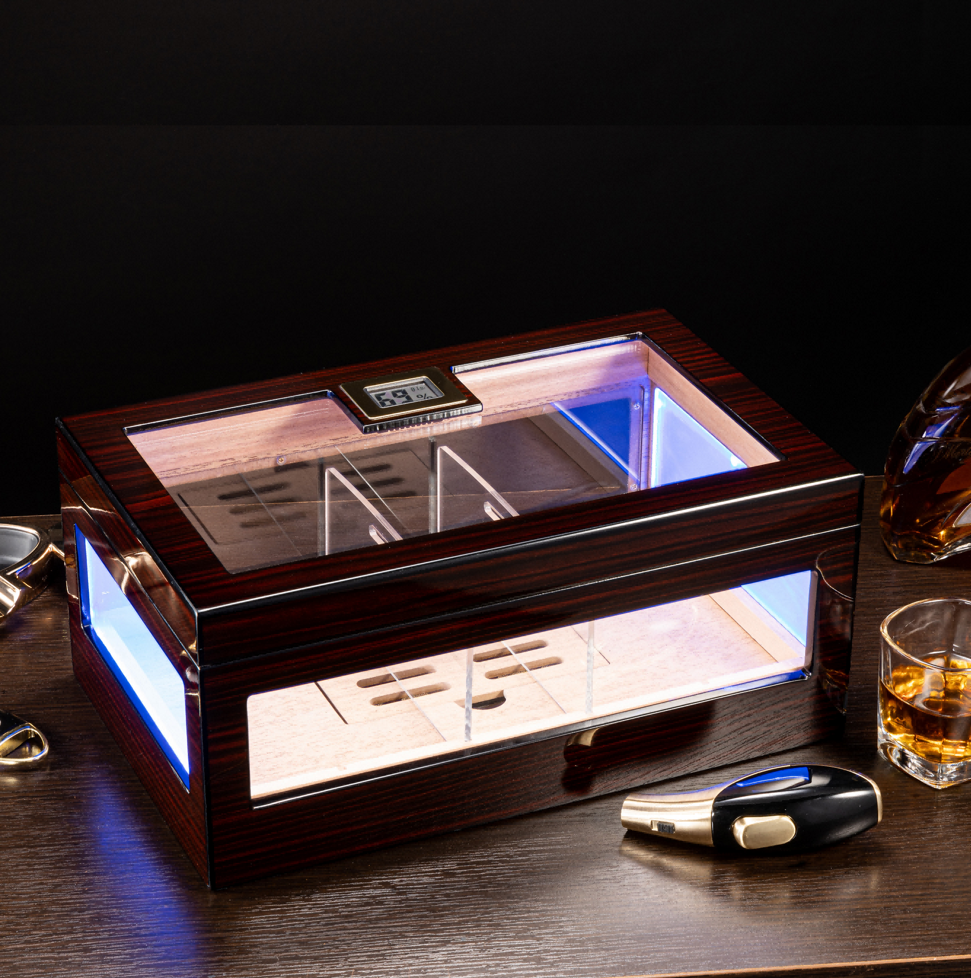 Ebony cigar humidor with LED lighting displayed on a desk, paired with cigar accessories and whiskey, ideal for luxury home bar decor.