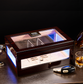Ebony cigar humidor with LED lighting displayed on a desk, paired with cigar accessories and whiskey, ideal for luxury home bar decor.