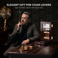 Sophisticated man enjoying a cigar beside the glossy ebony humidor, positioning it as an elegant gift for cigar lovers in a luxury study setting.