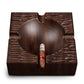 Close-up of square walnut ashtray holding a cigar, highlighting hand-carved details and functional rests.