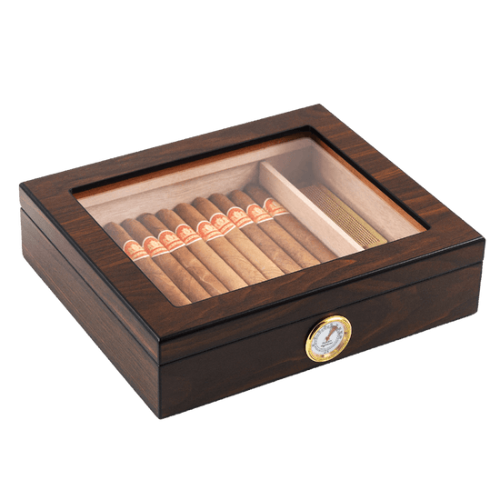 A closed dark wooden cigar humidor with a clear glass top, revealing neatly arranged cigars inside, featuring a gold-rimmed hygrometer on the front panel, set against a white background.