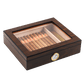 A closed dark wooden cigar humidor with a clear glass top, revealing neatly arranged cigars inside, featuring a gold-rimmed hygrometer on the front panel, set against a white background.
