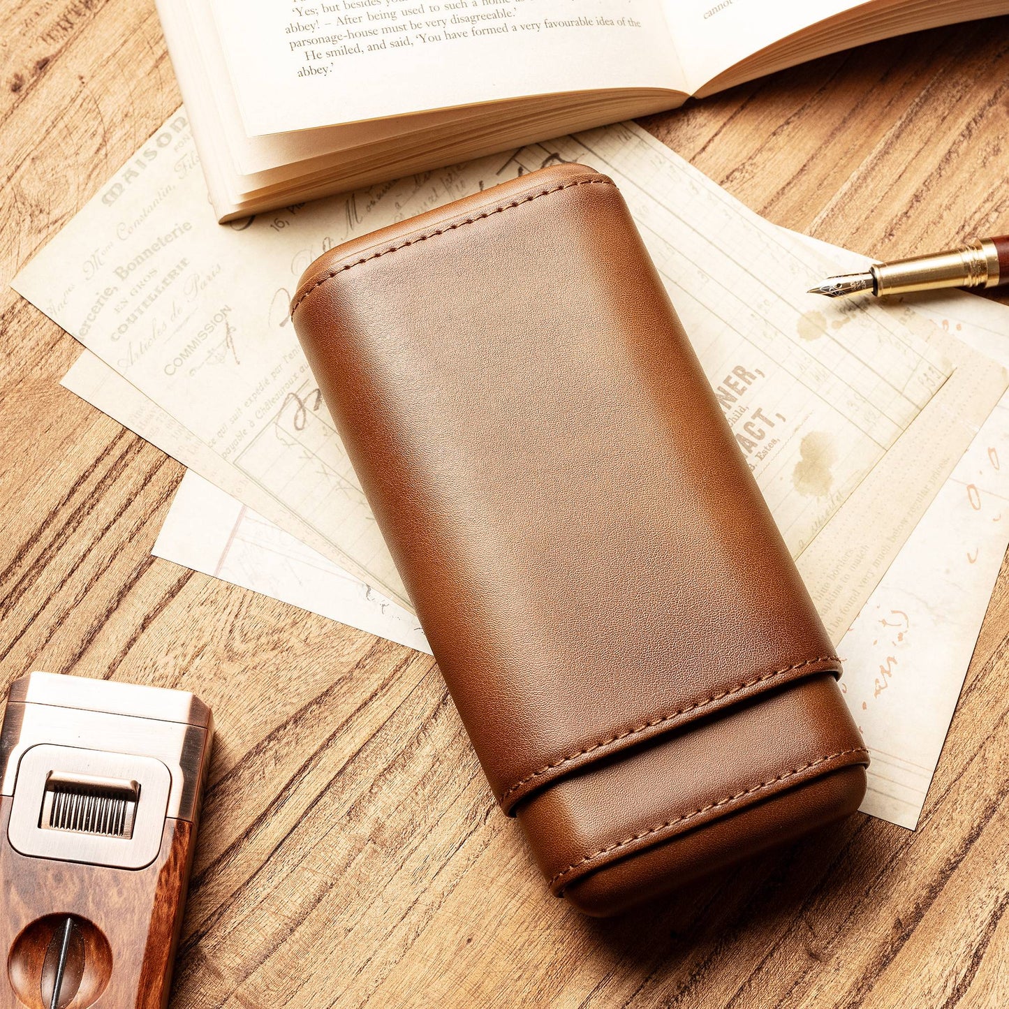 Fully closed brown leather cigar case with precise stitching, displayed next to a branded kraft gift box and a cigar cutter, ready for gifting.