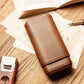 Fully closed brown leather cigar case with precise stitching, displayed next to a branded kraft gift box and a cigar cutter, ready for gifting.