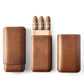 Top-down flat lay of three tan leather cigar cases: one open with three cigars, two closed, showcasing the product’s sleek design and capacity.