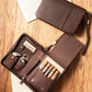 Open leather cigar case laid on a rustic wooden table, displaying its organized interior with five premium cigars, cutter, lighter, and humidifier, styled with vintage book pages.