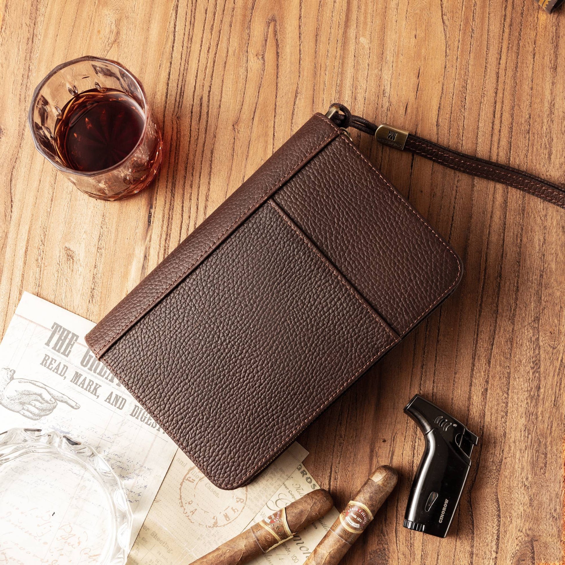 Closed cigar case styled with a crystal whiskey glass, cigar cutter, ashtray, and two premium cigars on a wooden table, creating a sophisticated gentleman’s lounge aesthetic.